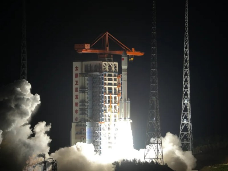 A Long March 6A rocket lifts off from the Taiyuan Satellite Launch Center in north China during a nighttime launch, with bright exhaust flames and billowing smoke illuminating the pad structure marked with Chinese characters.
