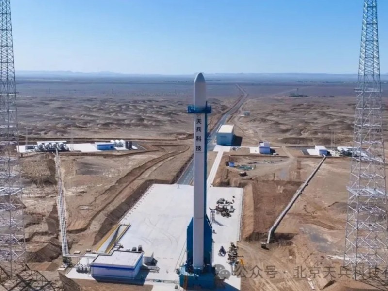 Full-scale mockup of Space Pioneer's Tianlong-3 rocket stands vertically on a newly completed launch pad at the Dongfeng Commercial Space Innovation Test Zone, located in the desert landscape of Jiuquan Satellite Launch Center. The launch pad is equipped with support towers, fueling infrastructure, and ground facilities visible under clear blue skies.
