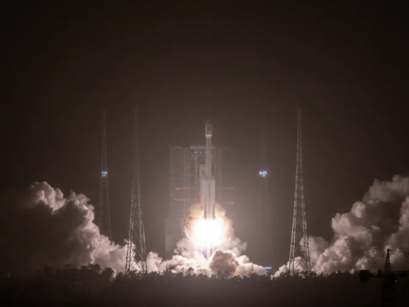 "A Long March 7A rocket lifts off at night from the Wenchang Satellite Launch Center, sending the classified TJS-16 satellite into orbit. Bright flames and thick plumes of exhaust illuminate the launch pad and surrounding towers against the dark sky.